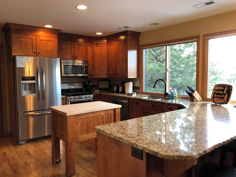 Kitchen with custom cabinetry, island, gas stove and granite countertop.  