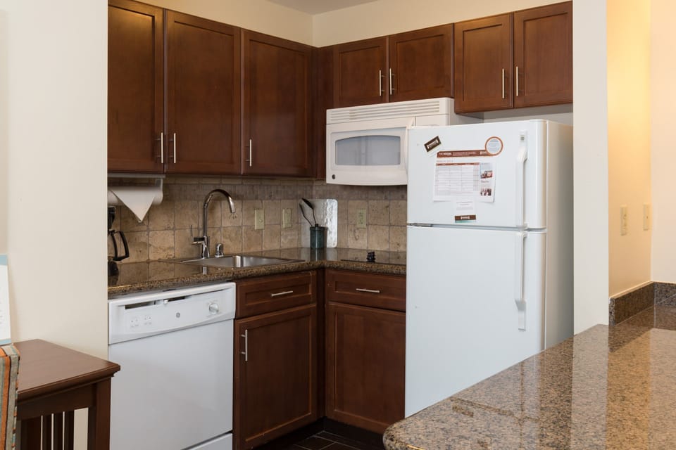 Kitchen with brown-tone cabinetry, full-size refrigerator, and a countertop beside the sink