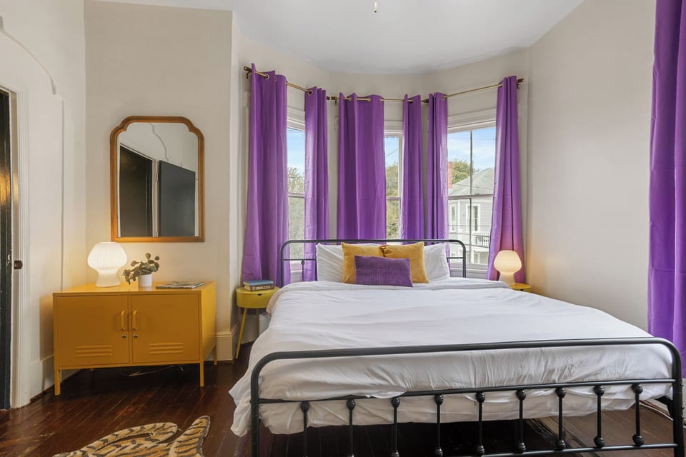 Spacious upstairs king bedroom featuring colorful pops of purple and yellow for a bright, cheerful feel.