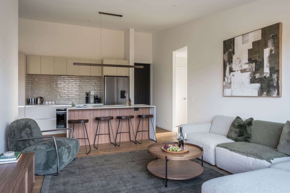 A bright, open-plan living, kitchen and dining space, beautifully finished in rich walnut and smooth stone.