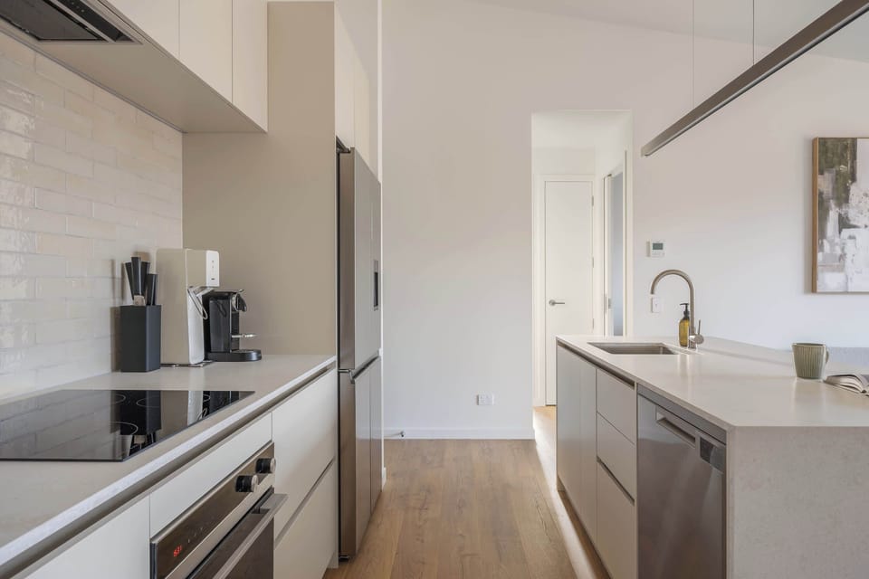 A bright, fully equipped kitchen, finished in warm neutrals and rich walnut.