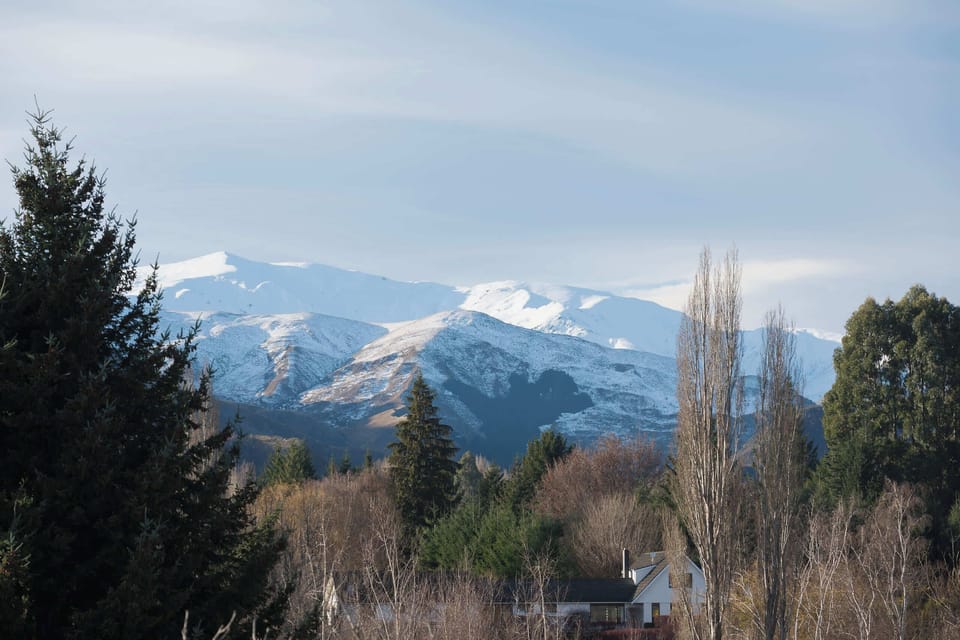 The snow-capped mountains, glimpsed across the tranquil, tree-lined grounds.