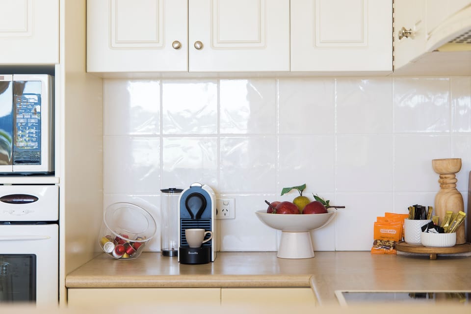 Bright kitchen with espresso machine, fruit, and a clean modern setup