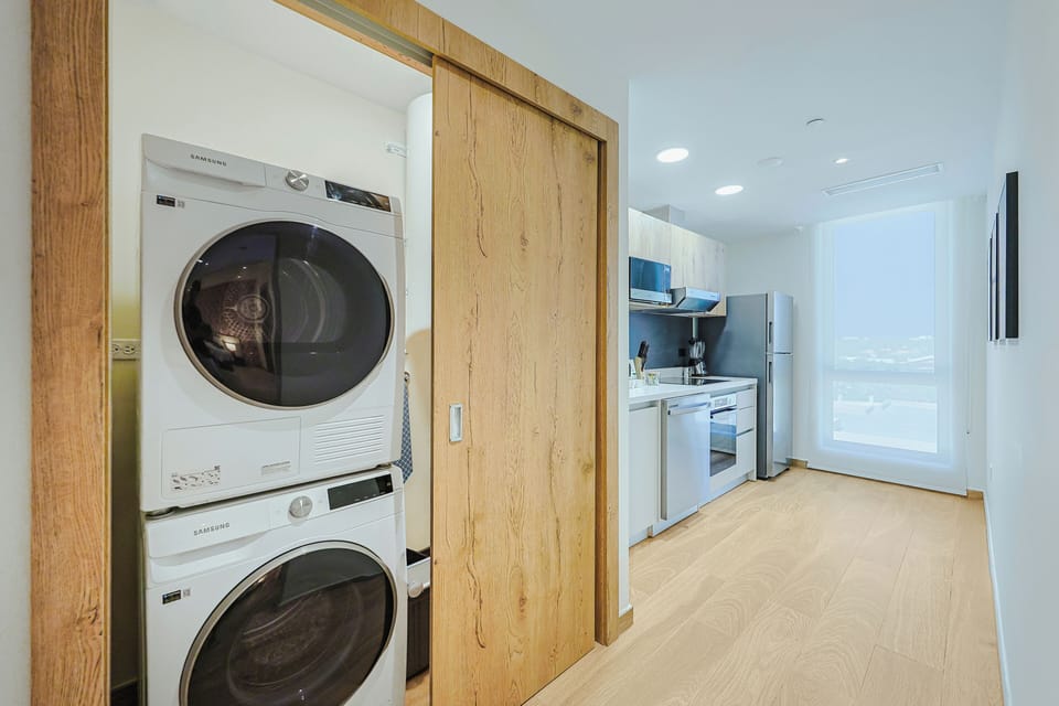 Your laundry closet features a stacked washer and dryer tucked neatly behind a sliding wood door, just steps from your modern kitchen equipped with stainless steel appliances and everything you'll need.