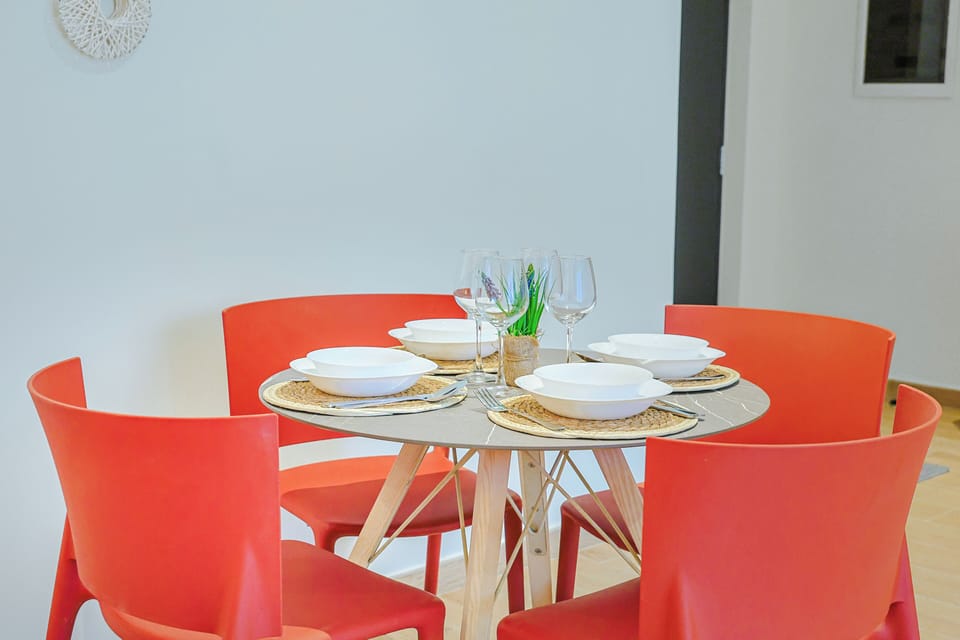 Your bright dining space awaits, thoughtfully set for memorable meals with vibrant modern chairs and a welcoming table, ready for laughter and togetherness.