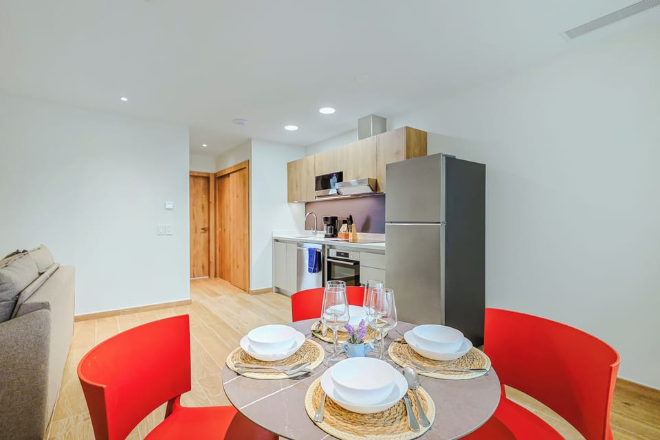 Gather around the sleek dining table set for four, with your bright modern kitchen just steps away—everything you need for effortless meals at home.