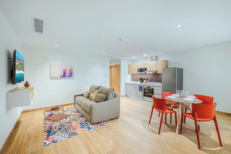 Step into your light-filled retreat, where modern design meets comfort. Unwind on your plush sofa, whip up meals in the sleek kitchen, and gather around the vibrant dining table for memorable moments during your stay.