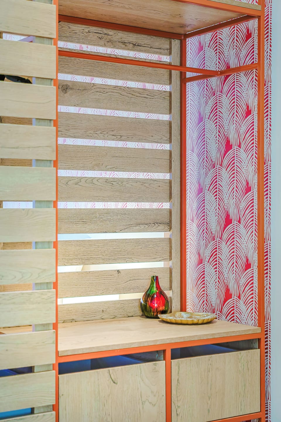 A cheerful wooden room divider with bold patterned wallpaper and orange metal framing adds a pop of personality to your stay.
