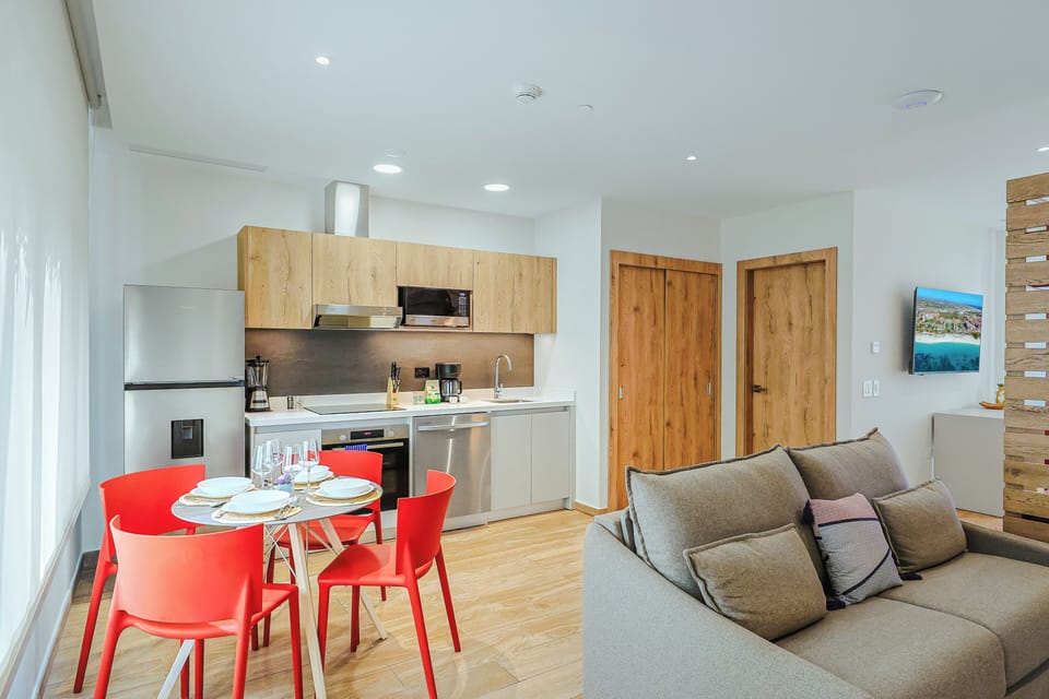 Your bright, open-plan sanctuary brings the kitchen, dining, and lounge together beautifully. Enjoy home-cooked meals at the cheerful red dining table or unwind on the cozy sofa, all bathed in natural light.