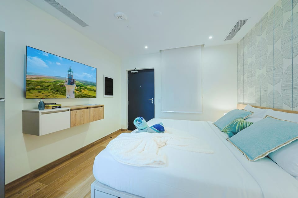 Relax in your serene bedroom with coastal-inspired décor, plush bedding, a large flat-screen TV, and soothing blue-green accents. Perfect for unwinding after exploring.