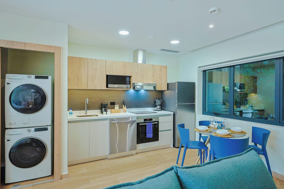 Modern open-plan space with sleek kitchen, vibrant dining area, and in-unit laundry—designed for your comfort and convenience during a relaxing stay.