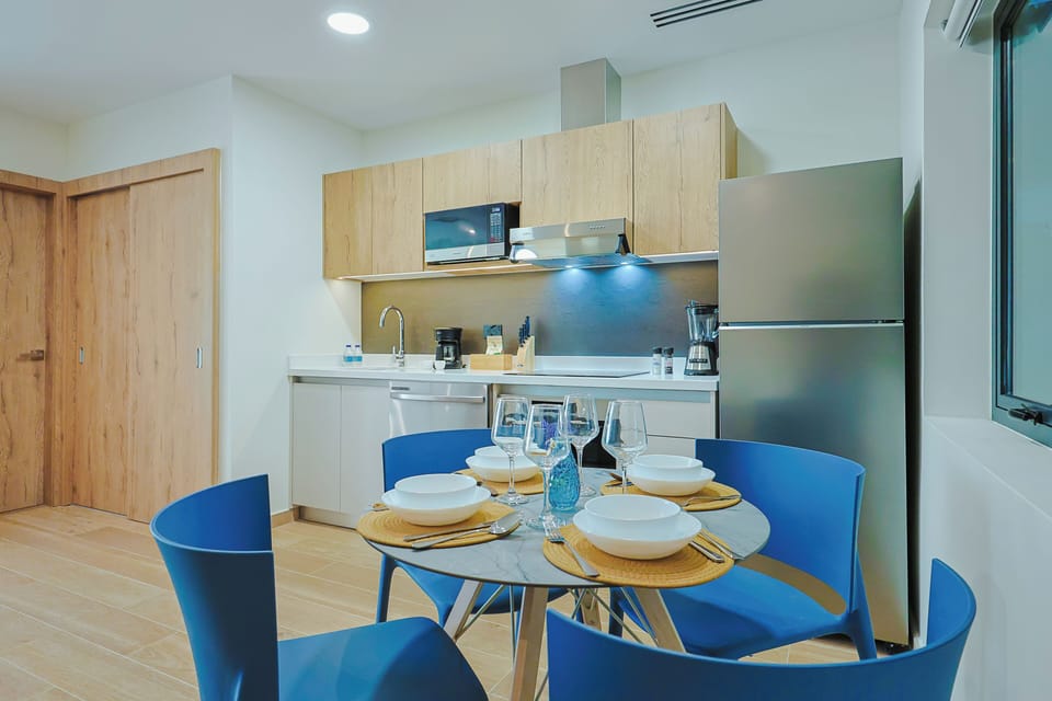 Gather around your fully equipped kitchen and dining space, complete with modern appliances and a cozy table set for four—perfect for preparing and enjoying meals together.