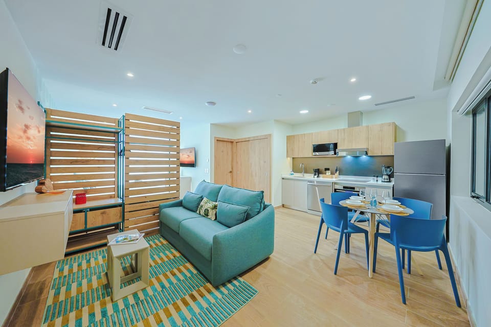 Your open-plan living space combines comfort and convenience with a cozy sofa, full kitchen, and bright dining area—perfect for relaxing or sharing meals together.