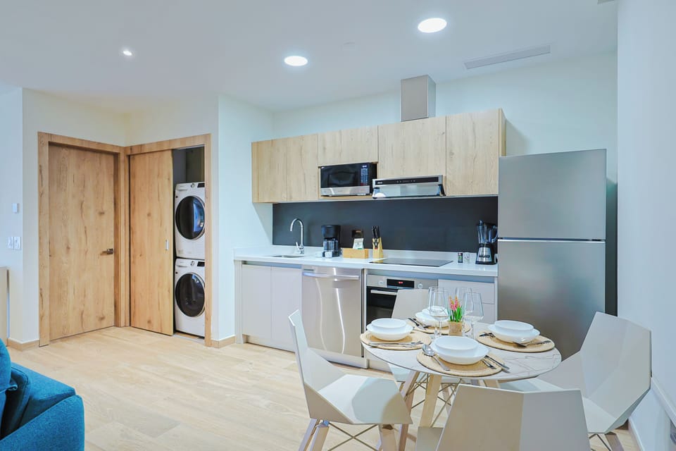 Your modern kitchen is fully equipped with sleek appliances, warm wood cabinetry, and a bright dining nook—perfect for preparing and enjoying meals together during your stay.