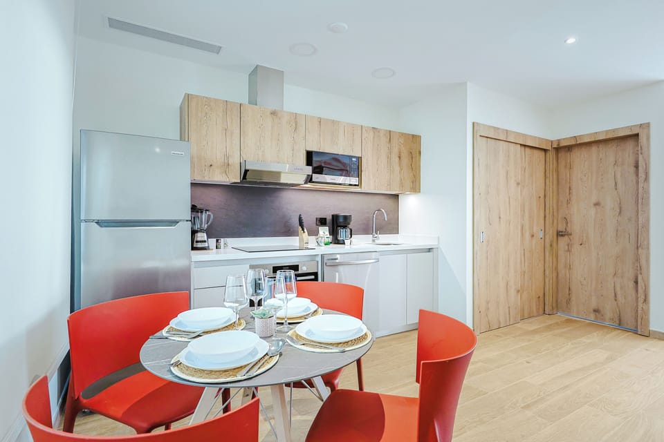 Gather around for meals in this sleek modern kitchen, featuring vibrant orange seating and contemporary wood-toned cabinetry. Your fully equipped space makes cooking easy and inviting.