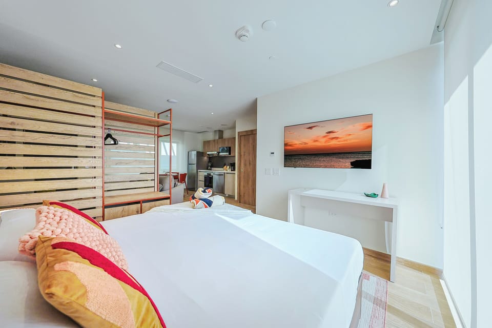 Your airy studio blends coastal comfort with modern design, featuring warm wood accents, a cozy bed, and an open kitchen ready for your arrival.