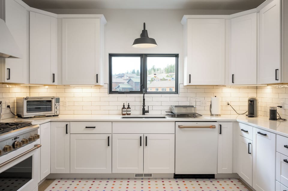 Step into your fully equipped kitchen featuring white cabinetry, modern appliances, and a charming window that frames neighborhood views as you prepare your favorite meals.