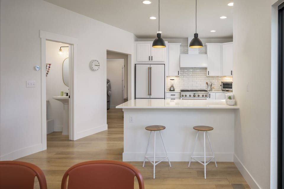 Step into your bright, modern kitchen with sleek white cabinets, stainless steel appliances, and a breakfast bar perfect for morning coffee or casual meals.