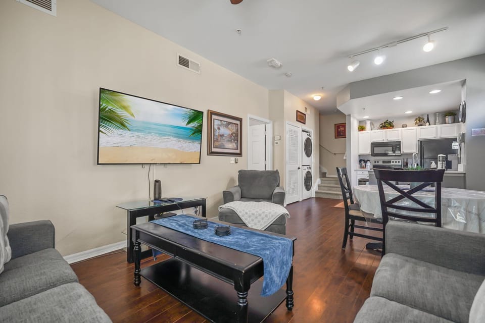 Living room with Smart TV, dining area, laundry area, & the kitchen in the back.