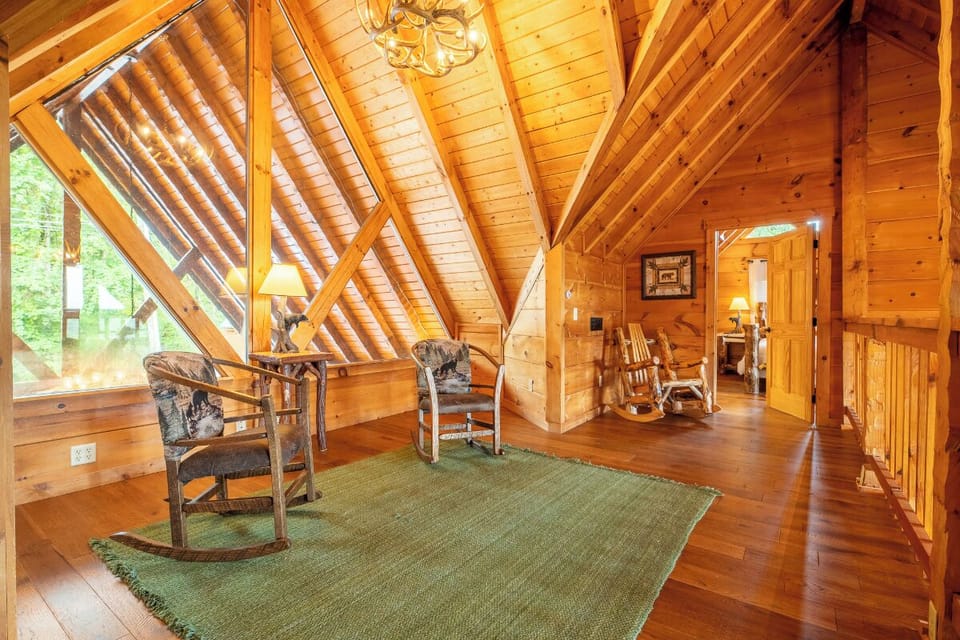 Step into the warmth of your private loft with soaring wood-beam ceilings and soft natural light filtering through tall windows. Relax in rustic charm with handcrafted furniture and peaceful forest views just beyond the glass.