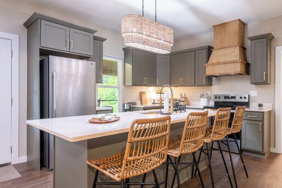 Step into your fully equipped kitchen, where sleek gray cabinetry meets warm wood accents and a spacious island invites you to gather with friends over coffee or cocktails.