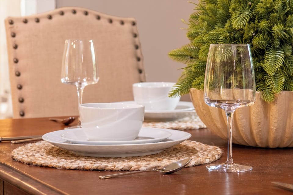 Your dining table is set with elegant white dishes, wine glasses, and natural touches—perfect for sharing meals together.