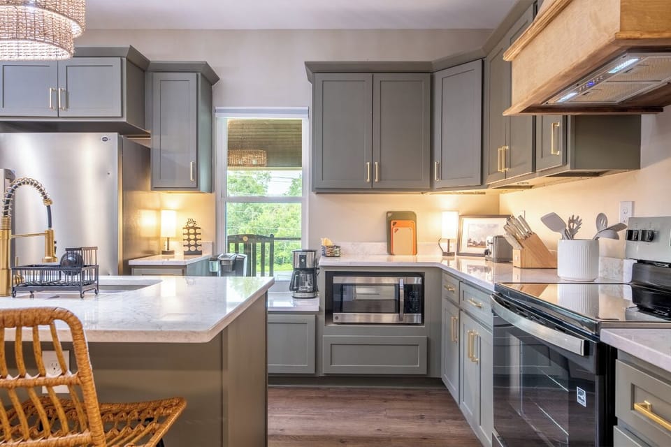 Your fully equipped kitchen features sleek gray cabinetry, marble countertops, and modern stainless appliances—perfect for whipping up your favorite meals with plenty of space to gather and cook together.