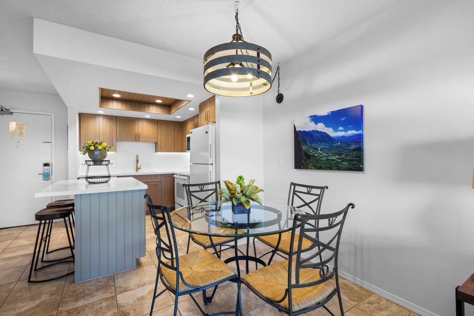 Step into your open-concept living space where warm wood tones meet coastal charm. Gather around the glass dining table or pull up a seat at the breakfast bar for morning coffee and easy conversation.