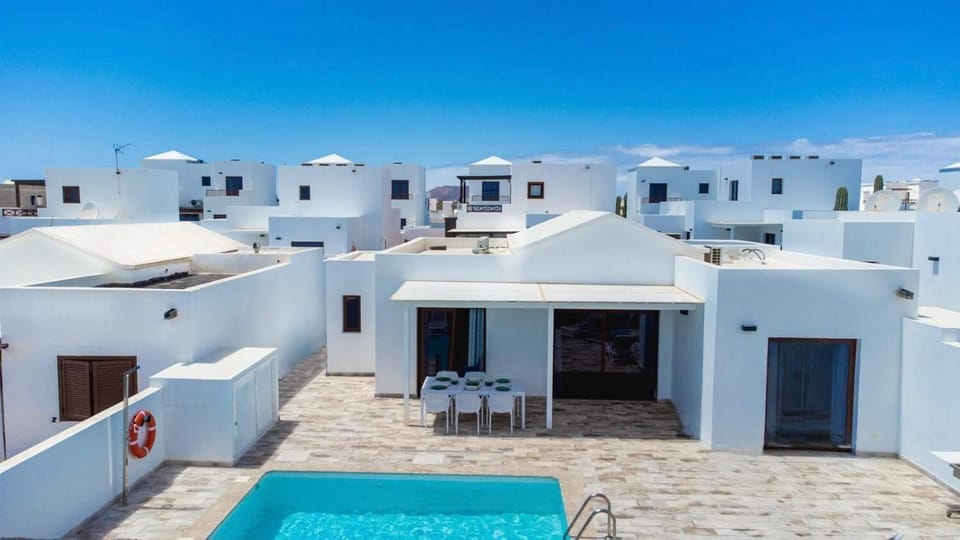 Modern white villa with a private swimming pool, spacious sun terrace, shaded outdoor dining area, and contemporary Mediterranean surroundings.