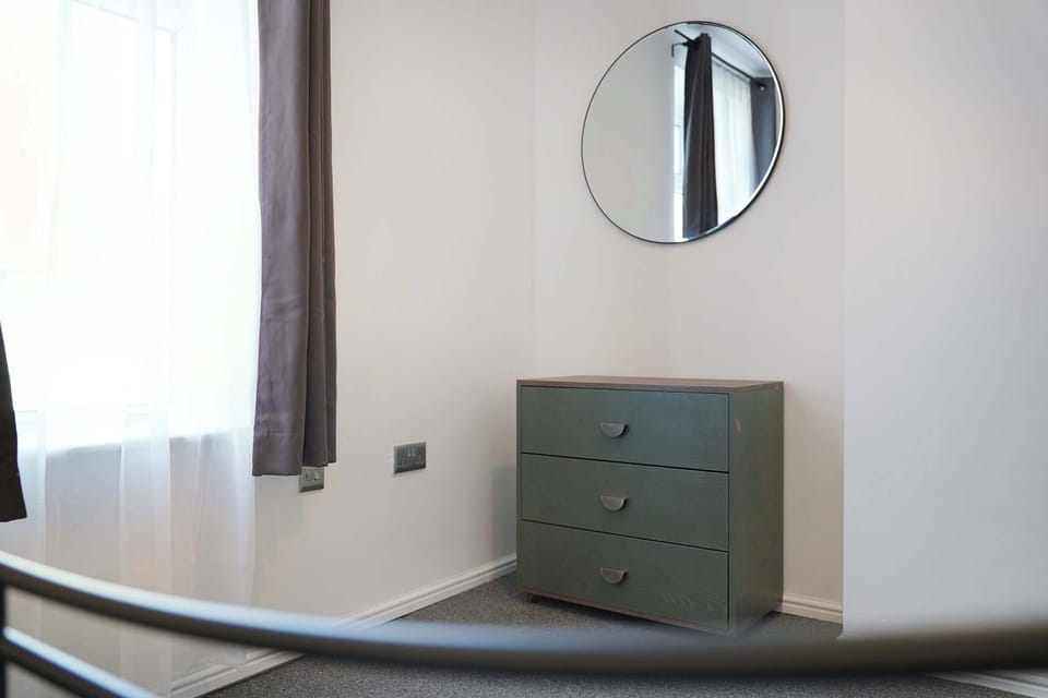 Designed with comfort and practicality in mind, the room offers a double bed, bedside table, and lamp. A clothes rail and chest of drawers provide useful storage, while a mirror completes the space for everyday convenience.