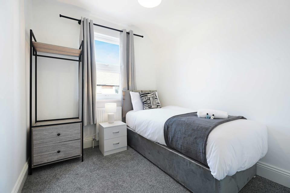 Designed for a comfortable stay, this single bedroom includes a single bed, a practical bedside table, a handy clothes hanging area, and storage for your belongings. A simple piece of wall art creates a warm and relaxing atmosphere.