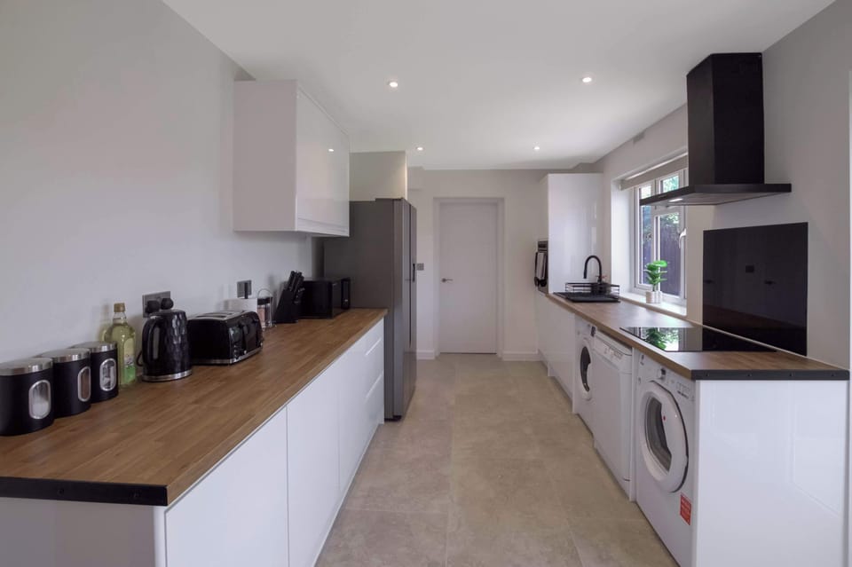 Modern, fully equipped kitchen with sleek white cabinetry, wooden countertops, integrated appliances, and a bright, spacious layout perfect for preparing meals during your stay.