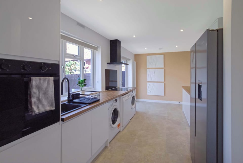 Modern, fully equipped kitchen with sleek white cabinetry, wooden countertops, integrated appliances, and a bright, spacious layout perfect for preparing meals during your stay.