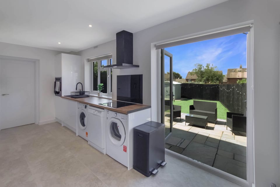 Modern, fully equipped kitchen with sleek white cabinetry, wooden countertops, integrated appliances, and a bright, spacious layout perfect for preparing meals during your stay.