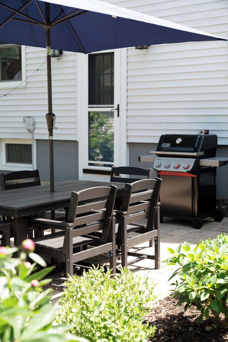 Private patio in fully-fenced back yard with natural gas Weber grill, dining table with umbrella, fire table, 6 Adirondak chairs, and yard games.