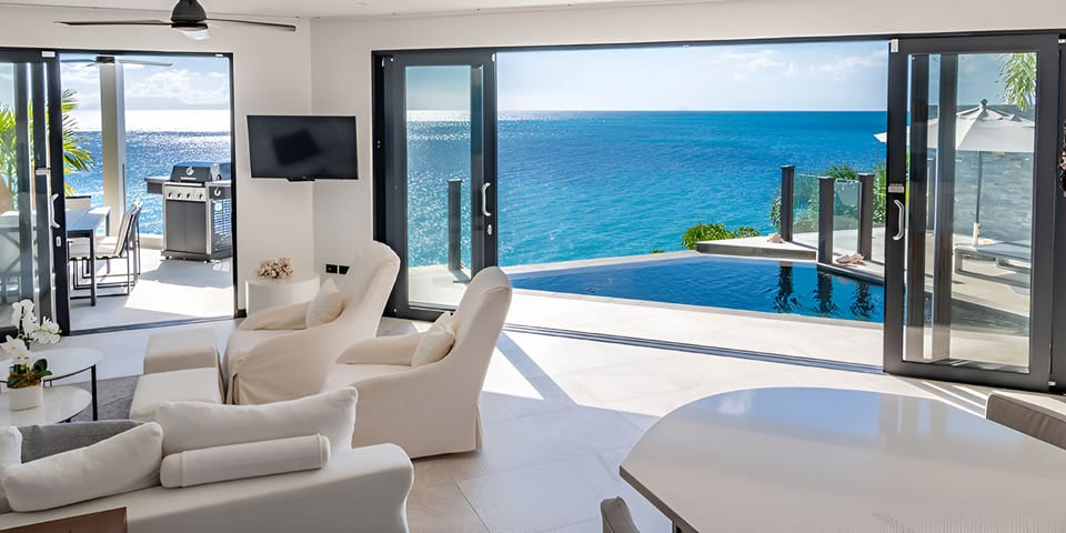 Lounge indoors as the infinity pool meets the horizon.