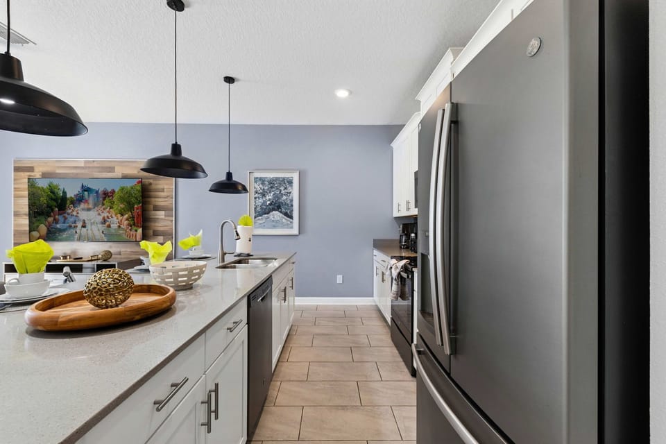 Sleek and modern kitchen with crisp white cabinetry, stainless appliances, and a bright breakfast bar-perfect for easy vacation meals and coffee mornings.