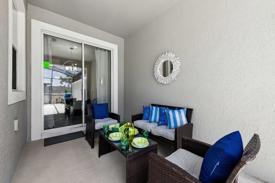 Enjoy a cozy covered patio with stylish wicker seating, cheerful blue accents, and easy access to the pool-an inviting spot to relax any time of day.