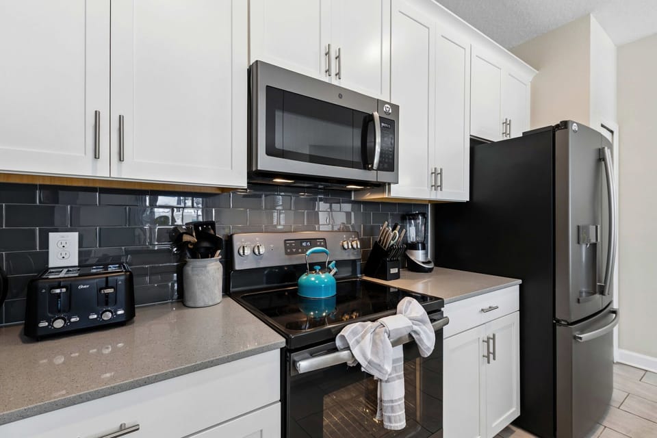 Cook with ease in this modern kitchen, featuring stainless appliances, glossy tile backsplash, and plenty of prep space for vacation meals.