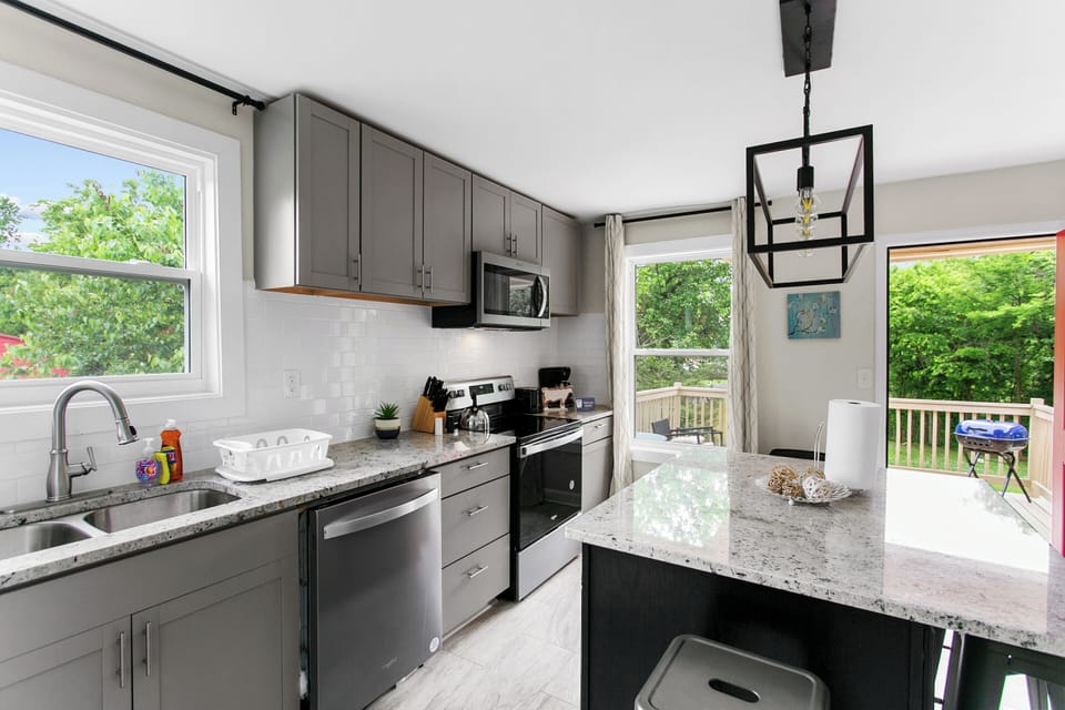 Cook, gather, and connect in Unit A's fully stocked kitchen featuring sleek granite countertops and a spacious island perfect for prepping, serving, or casual seating.