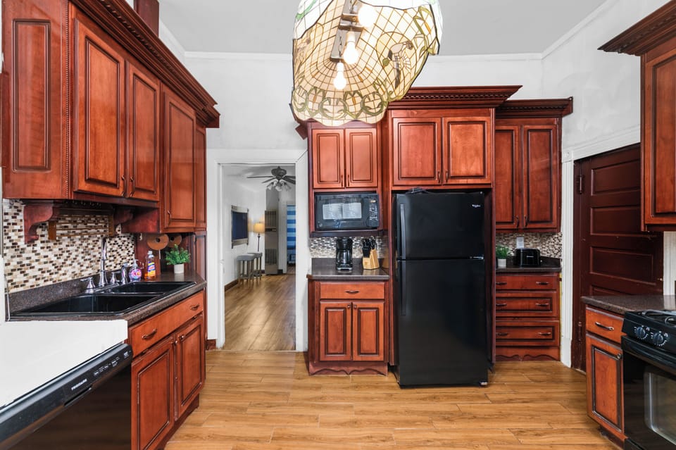Deep-toned cabinetry and detailed finishes give the kitchen a bold, classic presence, while open floor space keeps movement easy and natural during meal prep.