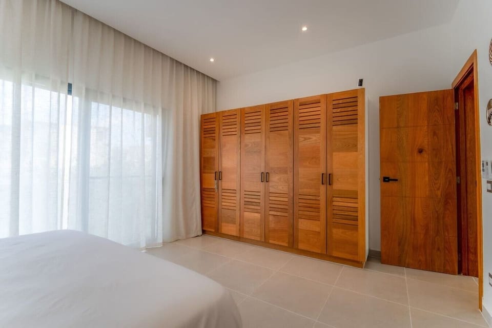 Bedroom 2 — Spacious storage with a full wall of built-in wooden wardrobes, keeping everything organized and within easy reach.