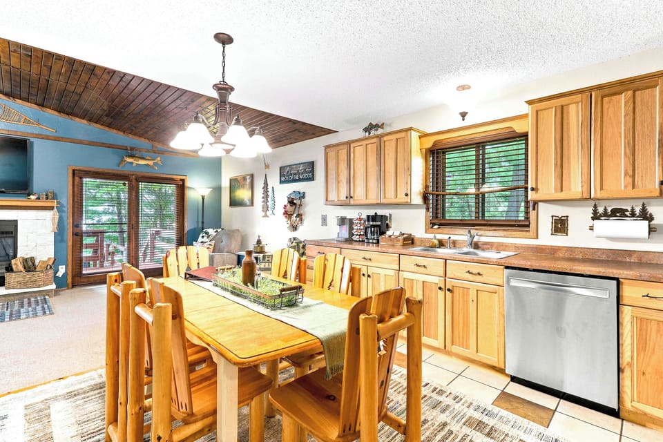 Gather for home-cooked meals in a fully equipped kitchen featuring stainless steel appliances and plenty of counter space. Share stories and morning coffee around the log-style dining table, surrounded by warm wood tones and charming cabin accents.