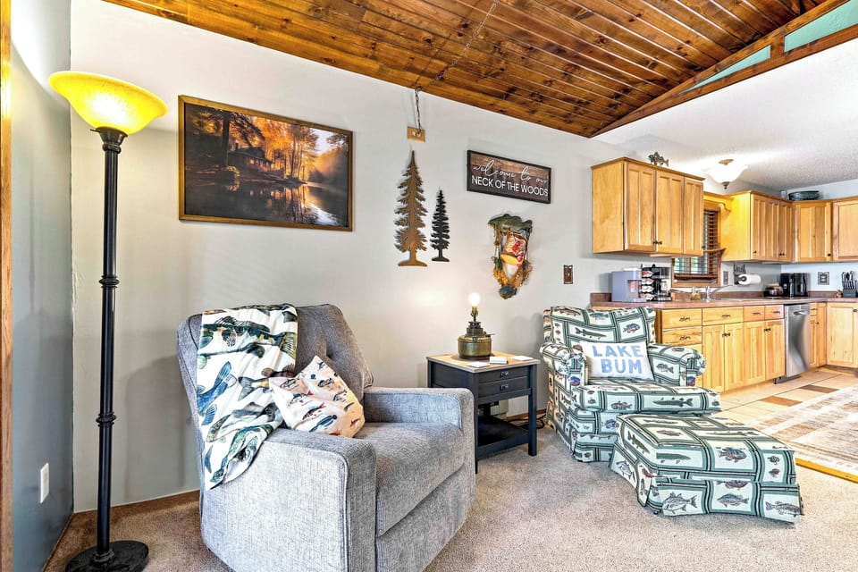 Relax in a cozy reading corner framed by warm wood ceiling panels and charming cabin decor. Curl up in the plush recliner or put your feet up on the matching armchair with ottoman while enjoying ambient glow from the floor lamp, creating the ultimate nook 