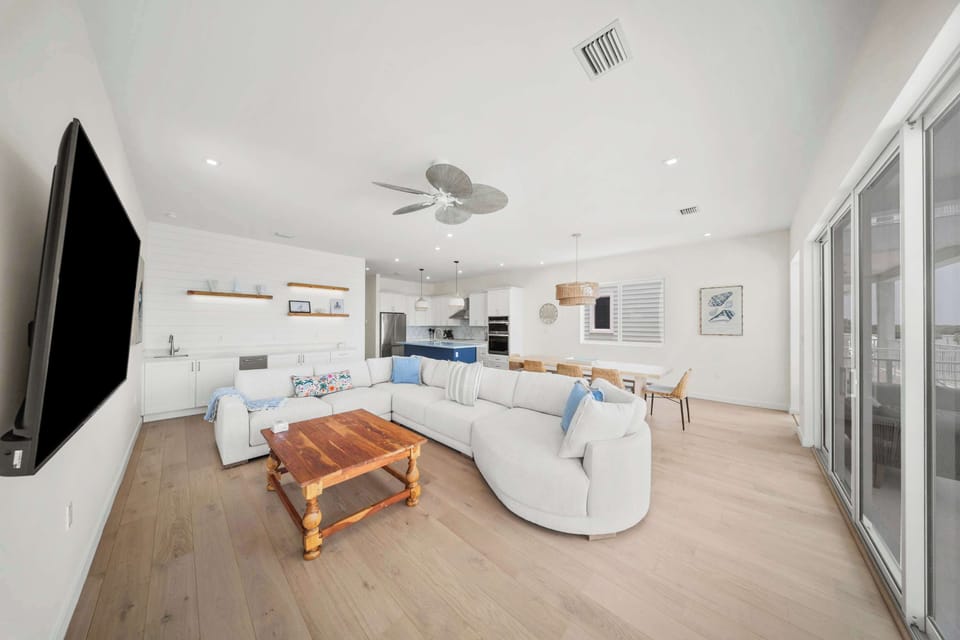 Gorgeous Living room with beautiful brand new furniture sectional and fully stocked kitchen enjoying the water views and spiral staircase to the outdoor oasis and pool area. 