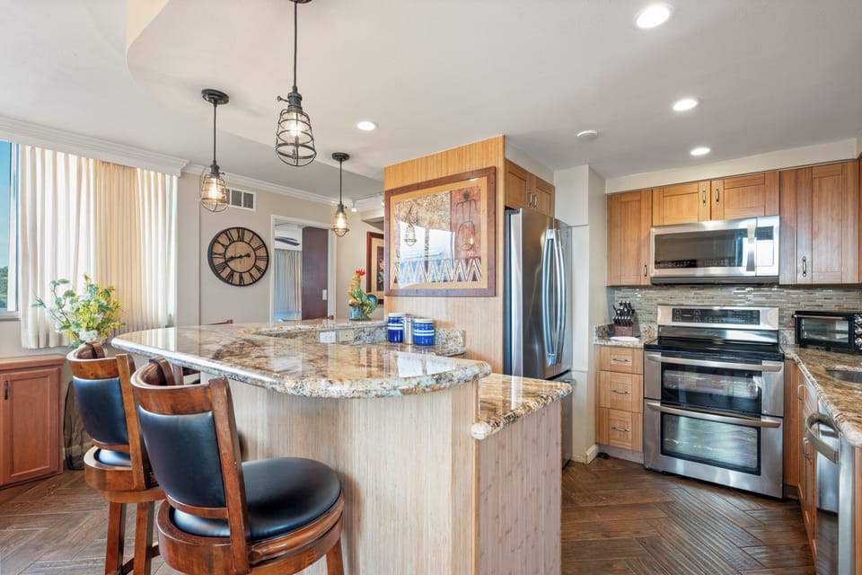 Bright, stylish kitchen featuring a spacious granite island, stainless appliances, and warm wood cabinetry. Pendant lights and natural light make it perfect for cooking, entertaining, and morning coffee.