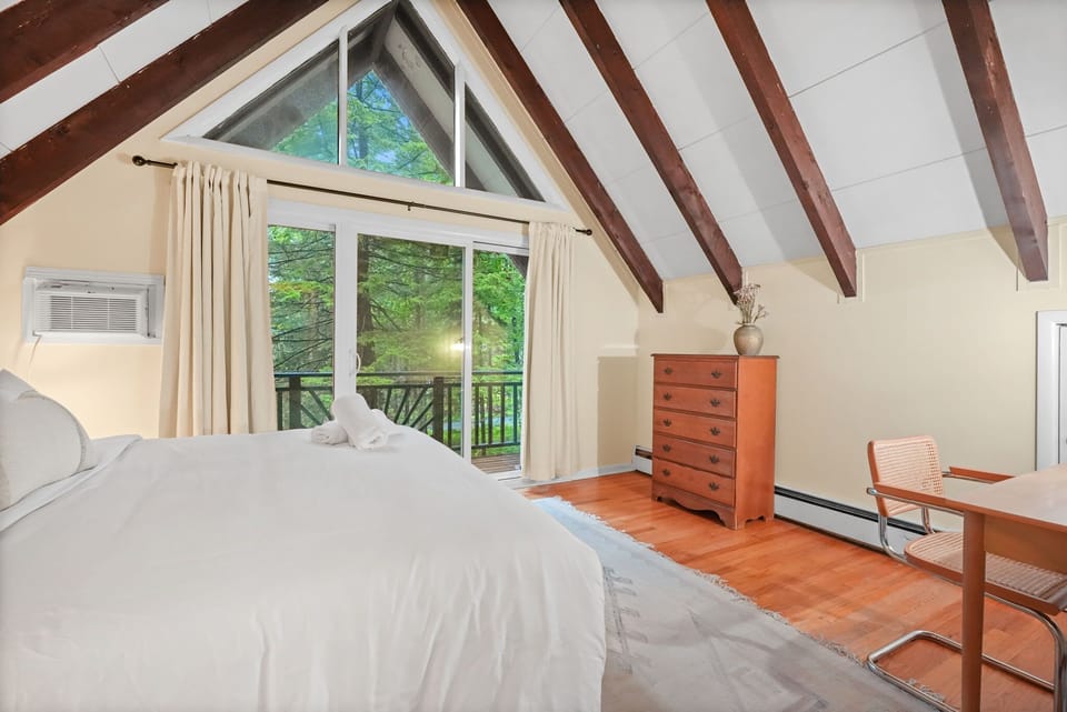 Upstairs queen bedroom with peaked A-frame window wall and private balcony access