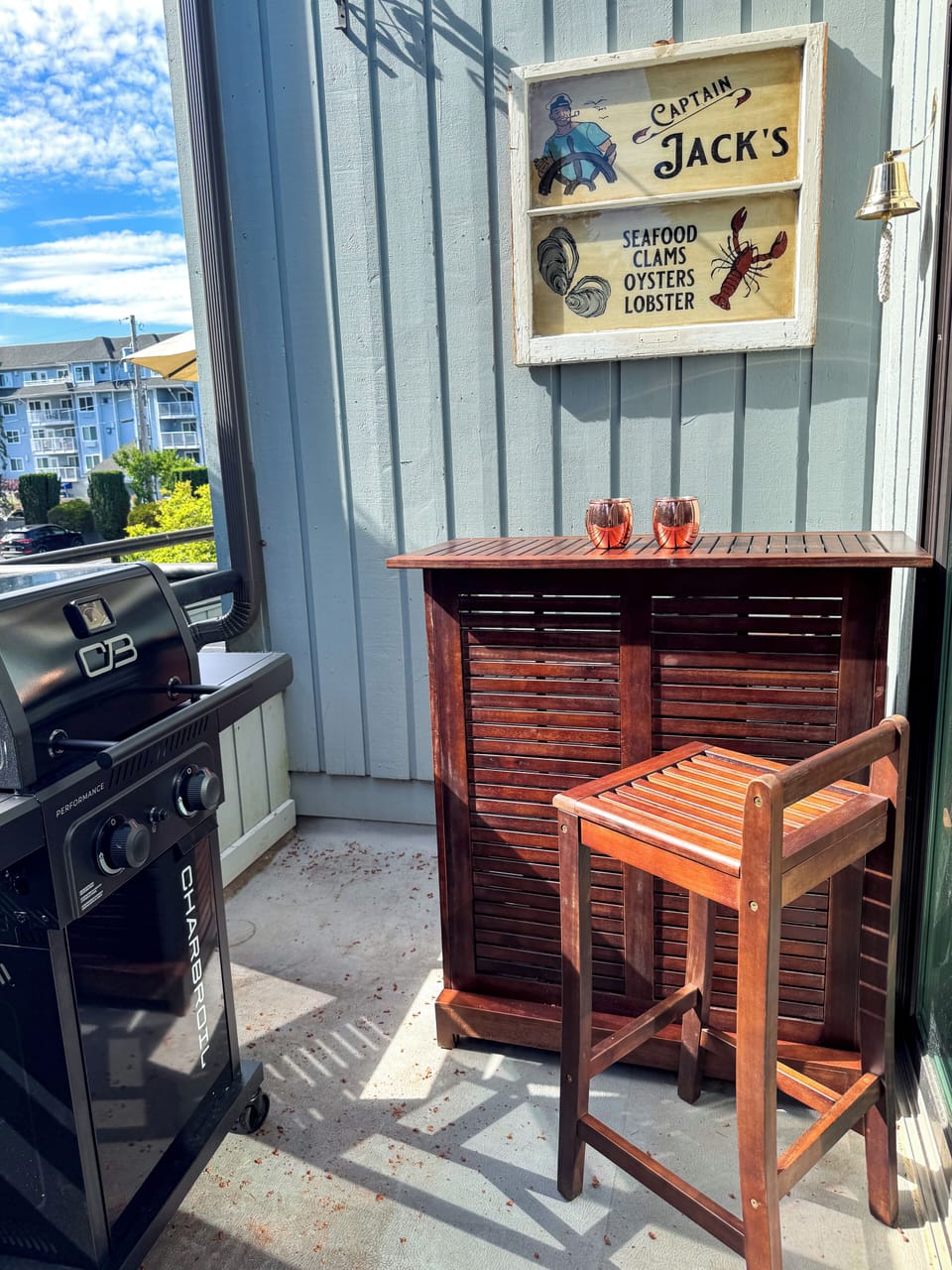Sunny private balcony with grill, bar, seating, and coastal charm