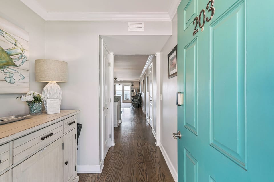 Step into your bright hallway where coastal charm meets modern comfort, featuring beautiful hardwood floors and a charming turquoise accent door.