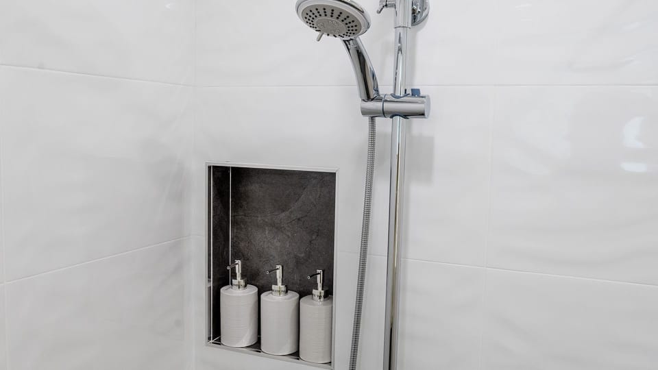 Walk-in shower featuring a recessed niche stocked with toiletries.